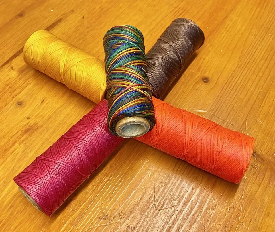 Bobinas de hilo encerado de colores sobre una mesa de madera